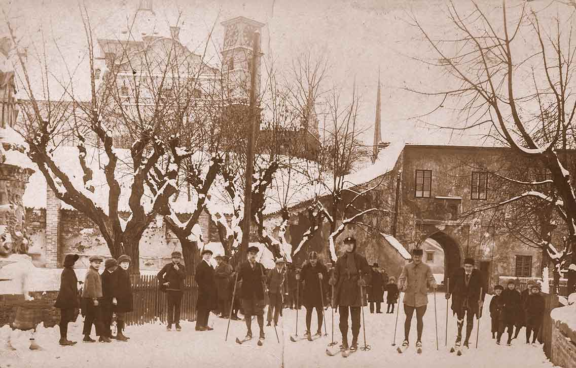 Pohled od východu na vstupní bránu zámku se skupinou lyžařů na zámeckém mostku, 1910